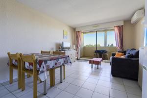 a living room with a table and chairs and a couch at Appartement clim piscine garage in Le Grau-du-Roi