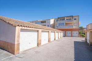 a row of white garage doors in front of a building at Appartement clim piscine garage in Le Grau-du-Roi
