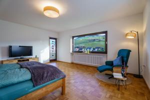a bedroom with a bed and a tv and a chair at Brandenkopfblick in Oberharmersbach
