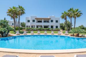 a swimming pool with chairs and a building in the background at Cala Egos Villa - S'Estel in Cala d´Or