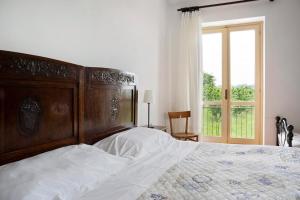 a bedroom with a large wooden bed and a window at Casa Pianezzo Dogliani in Dogliani