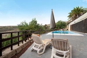 two chairs and an umbrella next to a swimming pool at Casa El Drago in Arico