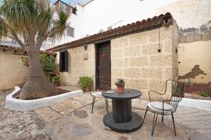 a patio with a table and chairs and a tree at Casa El Drago in Arico