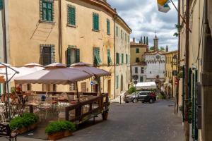 an alley with tables and umbrellas in a city at Residenza Palazzo Ghio in Scansano