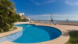 a blue swimming pool with chairs and a building at Na Penyal Ref 246 in Cala Millor
