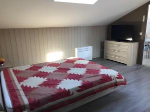 a bedroom with a bed and a dresser and a television at Loft Grand Confort Avec Piscine in Montalzat