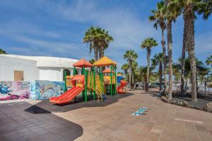 a playground with slides and palm trees in a park at Oasis Duna _ Casa Martineli Pool in Corralejo