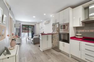 a kitchen with white cabinets and red counter tops at Apto Jardin del Sol Beach-Pool in Puerto de Santiago
