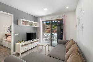 a living room with a couch and a tv at Apto Jardin del Sol Beach-Pool in Puerto de Santiago