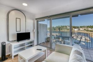 a living room with a couch and a tv and a balcony at 1a Linea mar port Llafranch in Llafranc