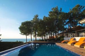 a swimming pool with chairs and the ocean in the background at Design villa with sea views in San Pol de Mar