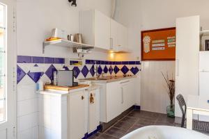 a kitchen with white cabinets and blue and white tiles at Casa de Jardim in Ponte de Sor +22 photos