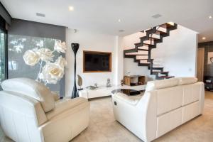 a living room with white furniture and a staircase at Design villa with sea views in San Pol de Mar