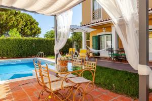a patio with a table and chairs next to a swimming pool at Casa de Jardim in Ponte de Sor