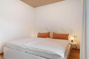 a white bedroom with a white bed with orange pillows at Wanderlust in Todtnau