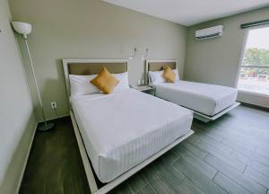 two beds in a room with white sheets and orange pillows at Hotel Royal Garden Tuxpan in Cobos