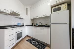 a kitchen with white cabinets and a refrigerator at Tirreno 304 in La Pineda