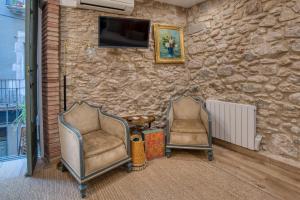 two chairs and a tv on a stone wall at Old Side Girona one in Girona