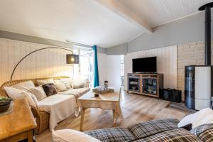 a living room with a couch and a tv at Demeure en pierre avec piscine in Vertheuil-en-Médoc