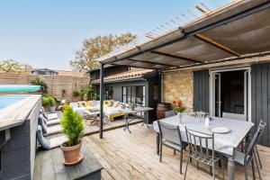 a patio with tables and chairs on a wooden deck at Demeure en pierre avec piscine in Vertheuil-en-Médoc