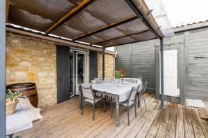 a patio with a table and chairs on a deck at Demeure en pierre avec piscine in Vertheuil-en-Médoc