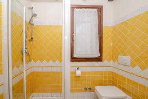 a yellow tiled bathroom with a toilet and a window at Residenza Conti Porto Istana in Porto Istana +19 photos