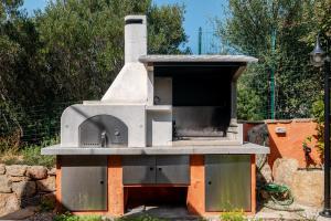 an outdoor pizza oven sitting in a garden at Residenza Conti Porto Istana in Porto Istana
