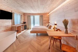 a bedroom with a bed and a tub in a room at Noah Suites in Vigo di Fassa
