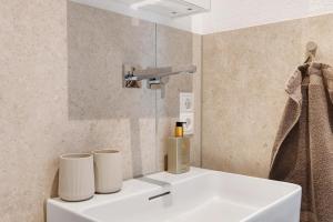 a bathroom with a sink with two cups on it at Bodensee Apartment Lindau in Lindau