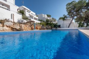 a swimming pool with blue water in front of buildings at Bungalow Cala Dor 27 in Cala d´Or