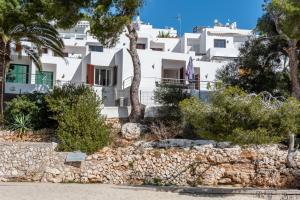a white building with trees and a stone wall at Bungalow Cala Dor 27 in Cala d´Or