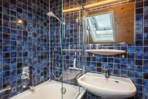 a blue tiled bathroom with a sink and a mirror at Haus Kremeier in Kressbronn am Bodensee
