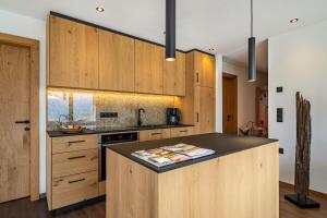 a kitchen with wooden cabinets and a black counter top at Sunnseitn Lodge Exclusive Panorama in Moso +11 photos