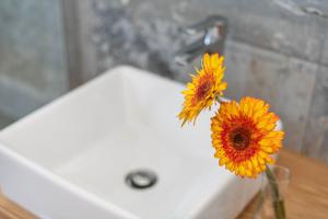two sunflowers in a vase on a bathroom sink at Casa Majina in El Islote