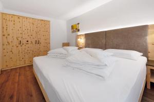 a large white bed with white sheets and pillows at Apartments Antersi Claudia in San Vigilio Di Marebbe