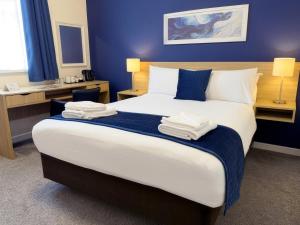 a bedroom with a large bed with blue walls at The Esplanade Hotel by Compass Hospitality in Paignton