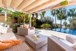 an outdoor patio with white furniture and a swimming pool at Alcanada Paradise in Alcudia