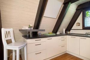 a kitchen with white cabinets and a white chair at Ferienhaus Exquisit in Immenstaad am Bodensee +15 photos