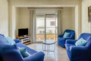 a living room with two blue chairs and a tv at Apartamento la Siesta in L'Escala