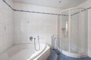 a white bathroom with a tub and a shower at Teichmühle - Vogtland Chalet in Bad Brambach +19 photos