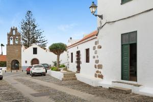 a white building with a green door and a church at Casa Mamayana in Telde
