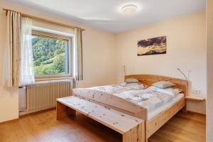 a bedroom with a wooden bed and a window at Oberhemberger Hof Feldthurns in Feldthurns