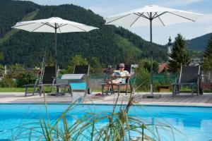 a woman sitting in a chair next to a swimming pool at Bramsauerhof in Faistenau