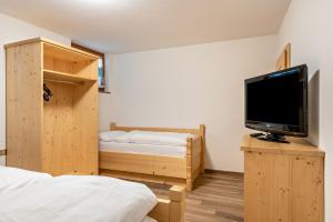 a room with two beds and a flat screen tv at Muncion Apparte in Pozza di Fassa
