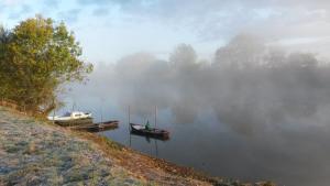 two boats are docked on a misty lake at Chambres D'hôtes Le Fer À Cheval in Montreuil-sur-Maine