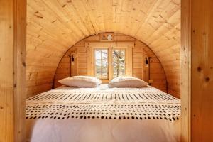 a bed in a log cabin with a window at Les Chouchous du Garthieu in Hourtin