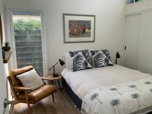 a bedroom with a bed and a chair and a window at The G Shack at Rennies Beach in Ulladulla