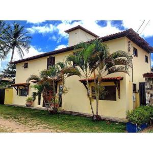 a white house with palm trees in front of it at Pousada Laguna Mar in Marechal Deodoro