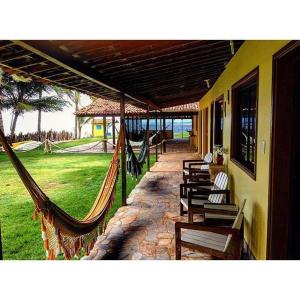 - une terrasse couverte avec des chaises et des hamacs dans un bâtiment dans l'établissement Pousada Laguna Mar, à Marechal Deodoro