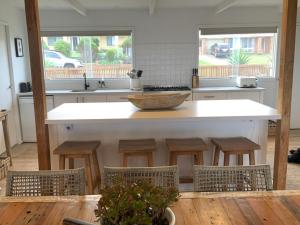 a kitchen with a large white island with stools at The G Shack at Rennies Beach in Ulladulla